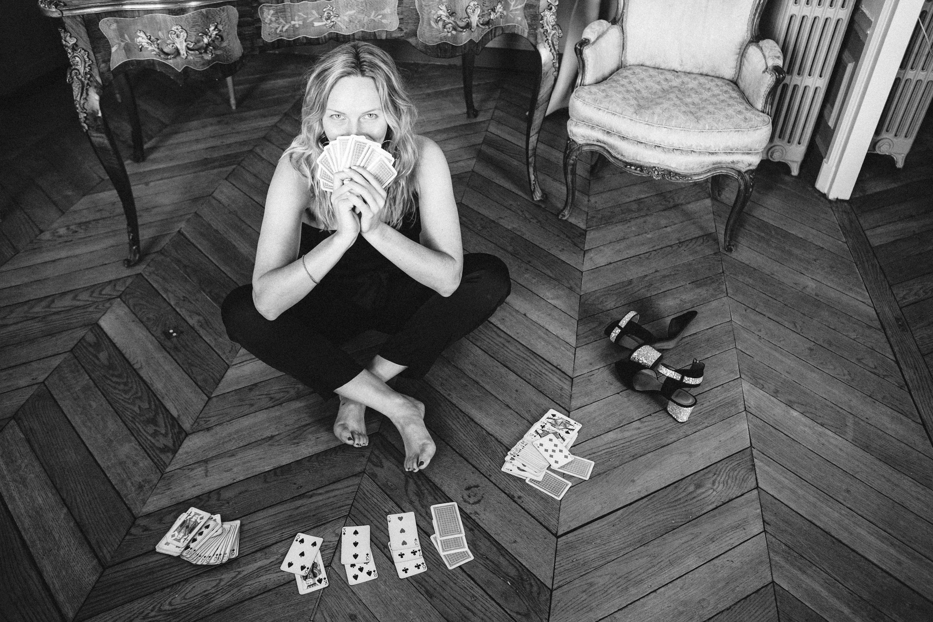Film noir portrait of a woman with playing cards in monochrome in a Paris flat, atmospheric black and white photography by Carla Coulson
