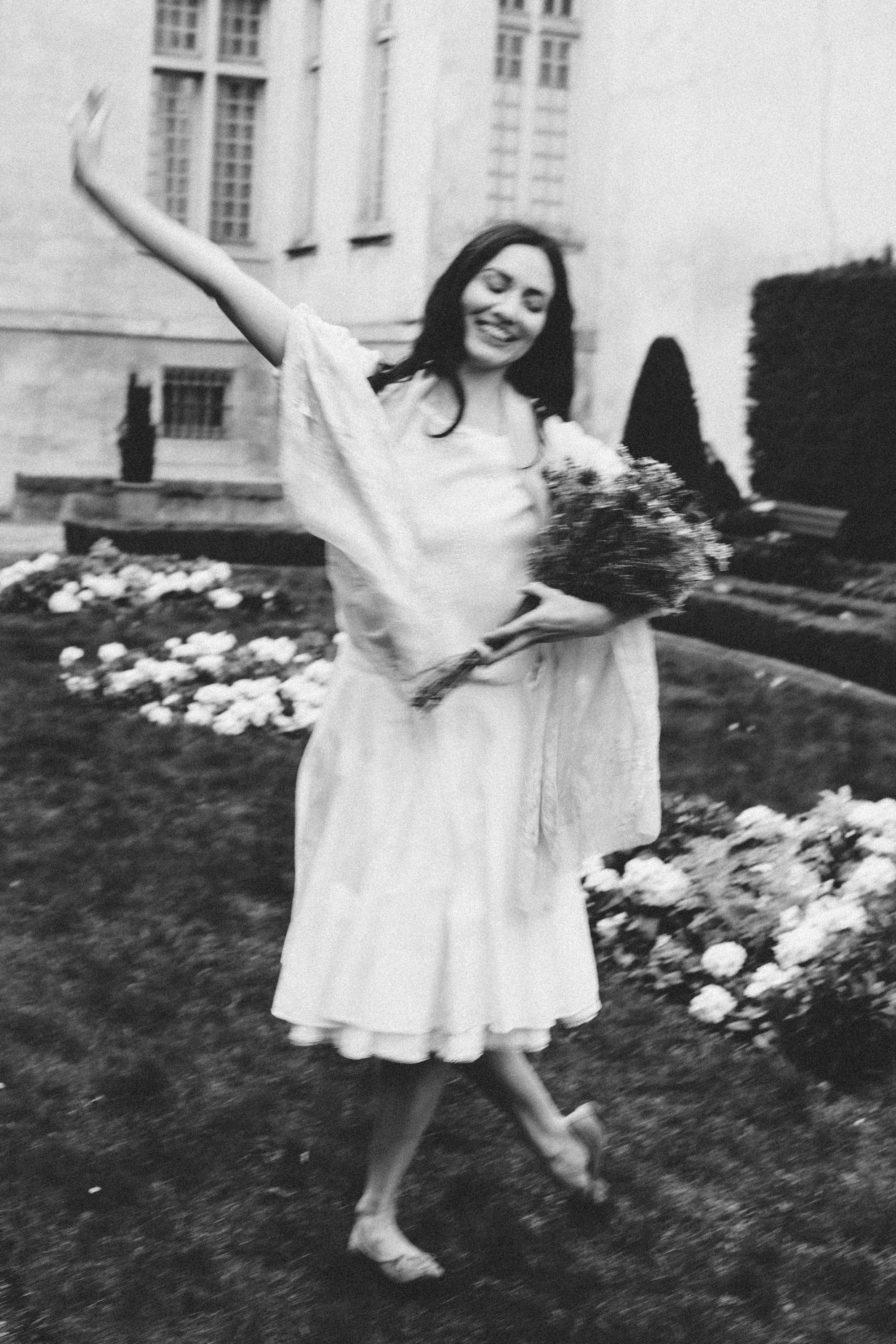 Woman in a white dress holding flowers in a Paris garden setting, film noir style by Carla Coulson