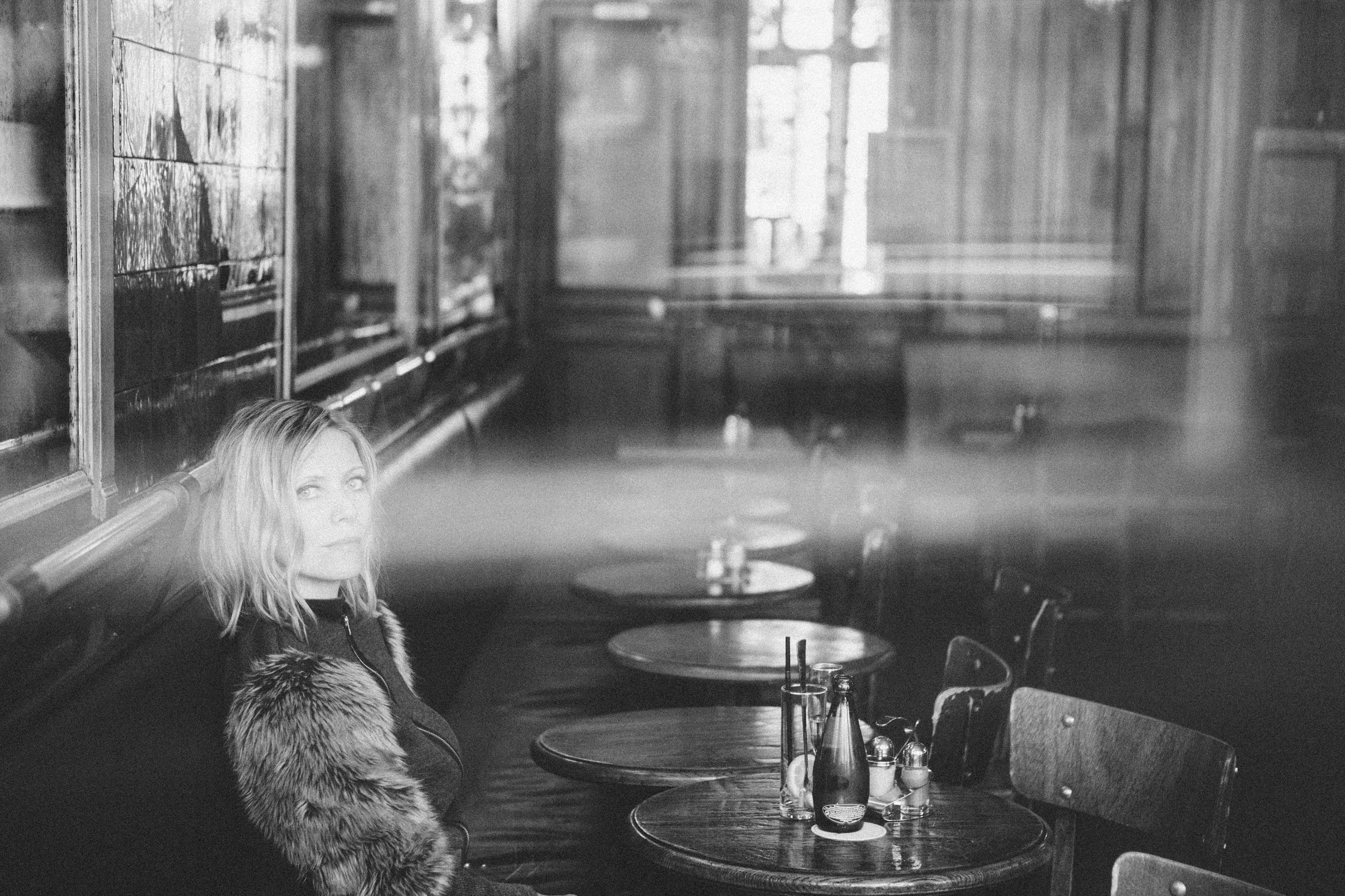 Evocative film noir portrait of a woman in a Paris cafe, atmospheric monochrome photography by Carla Coulson