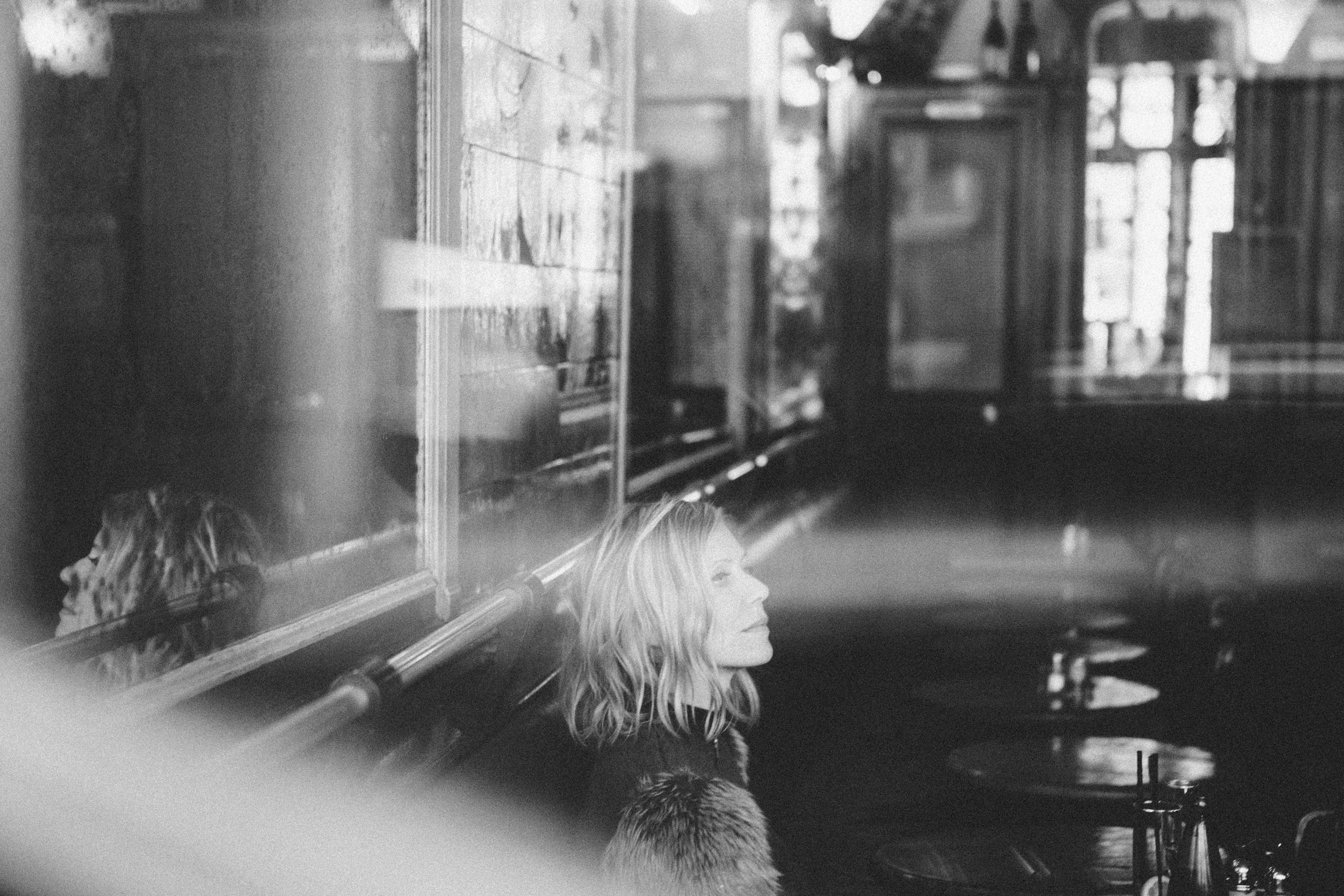 Atmospheric monochrome portrait of a woman in a Paris café, film noir style photography by Carla Coulson