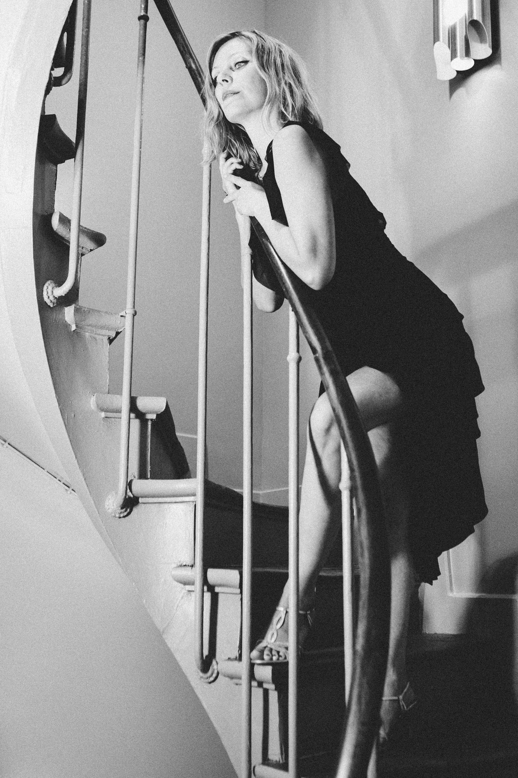Film noir portrait of a woman in a shadowy Parisian interior, black and white photography by Carla Coulson