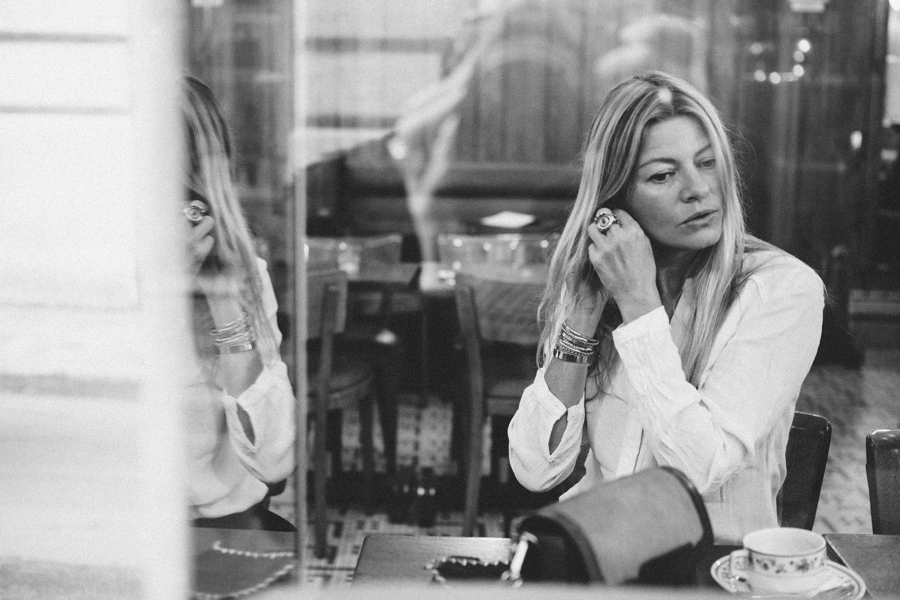 Moody wide-format black and white film noir portrait of a woman in a Paris cafe, photography by Carla Coulson