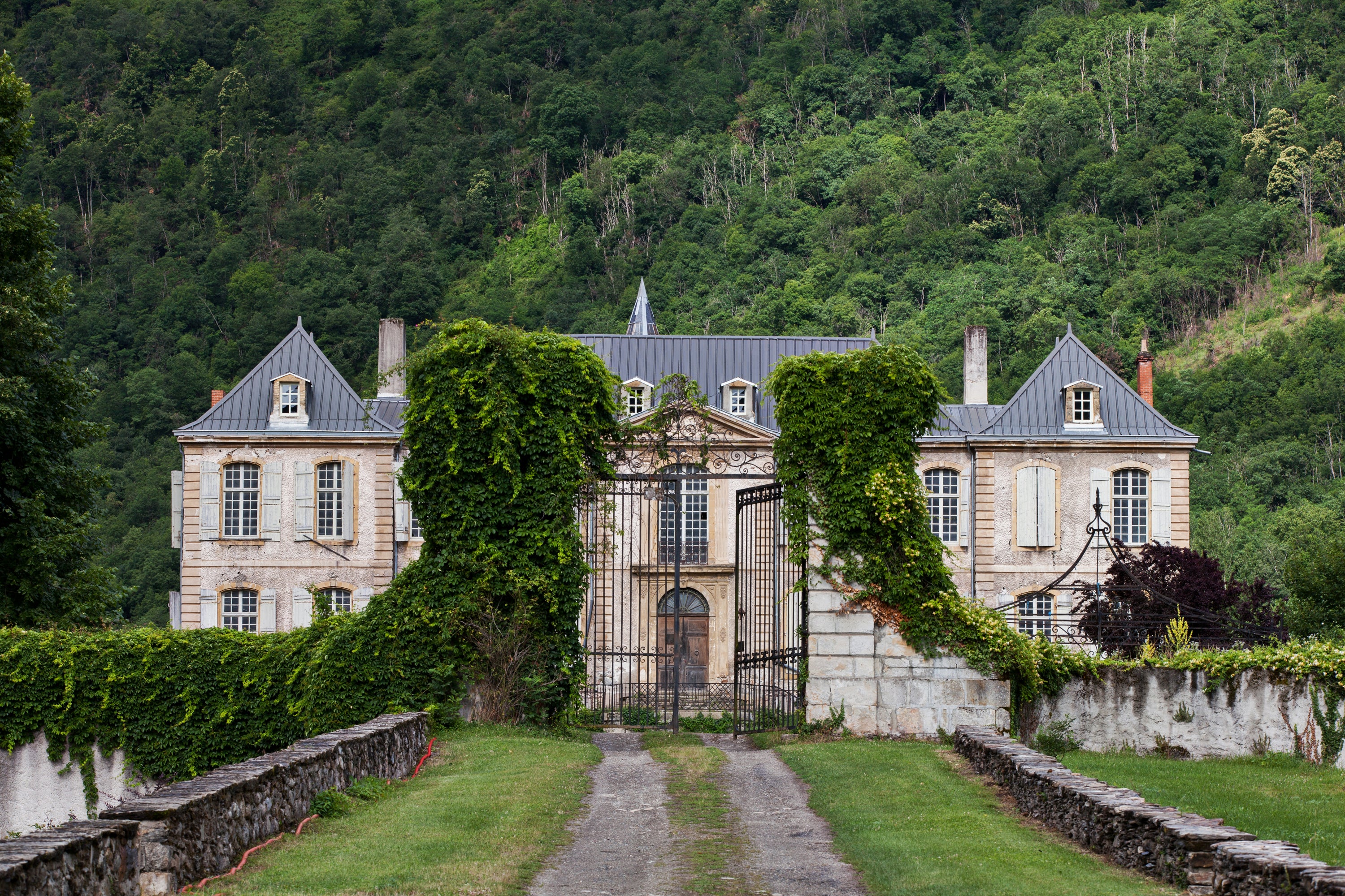 Large French chateau with greenery in a mountainous area — lifestyle photography by Carla Coulson