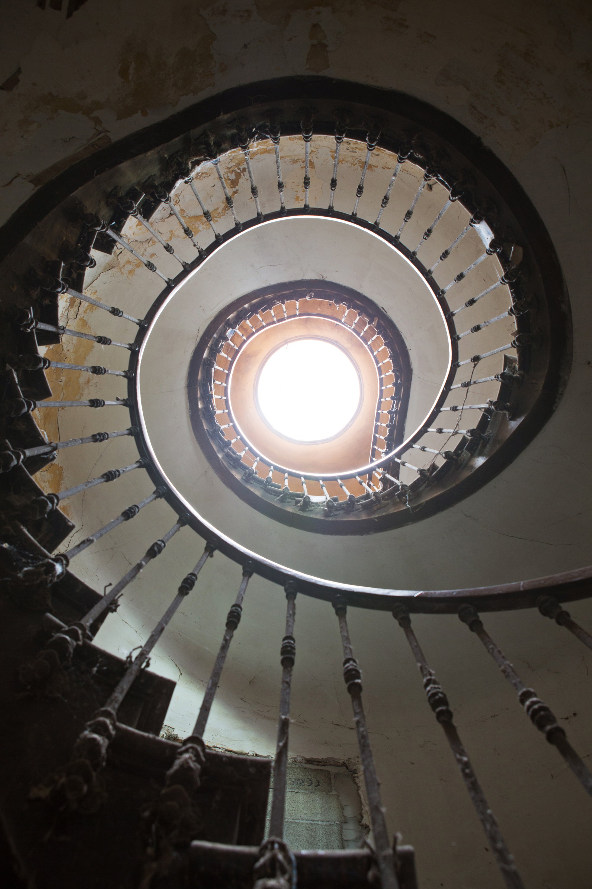 Stairwell with a spiral staircase leading to a bright light at the top — editorial photography by Carla Coulson