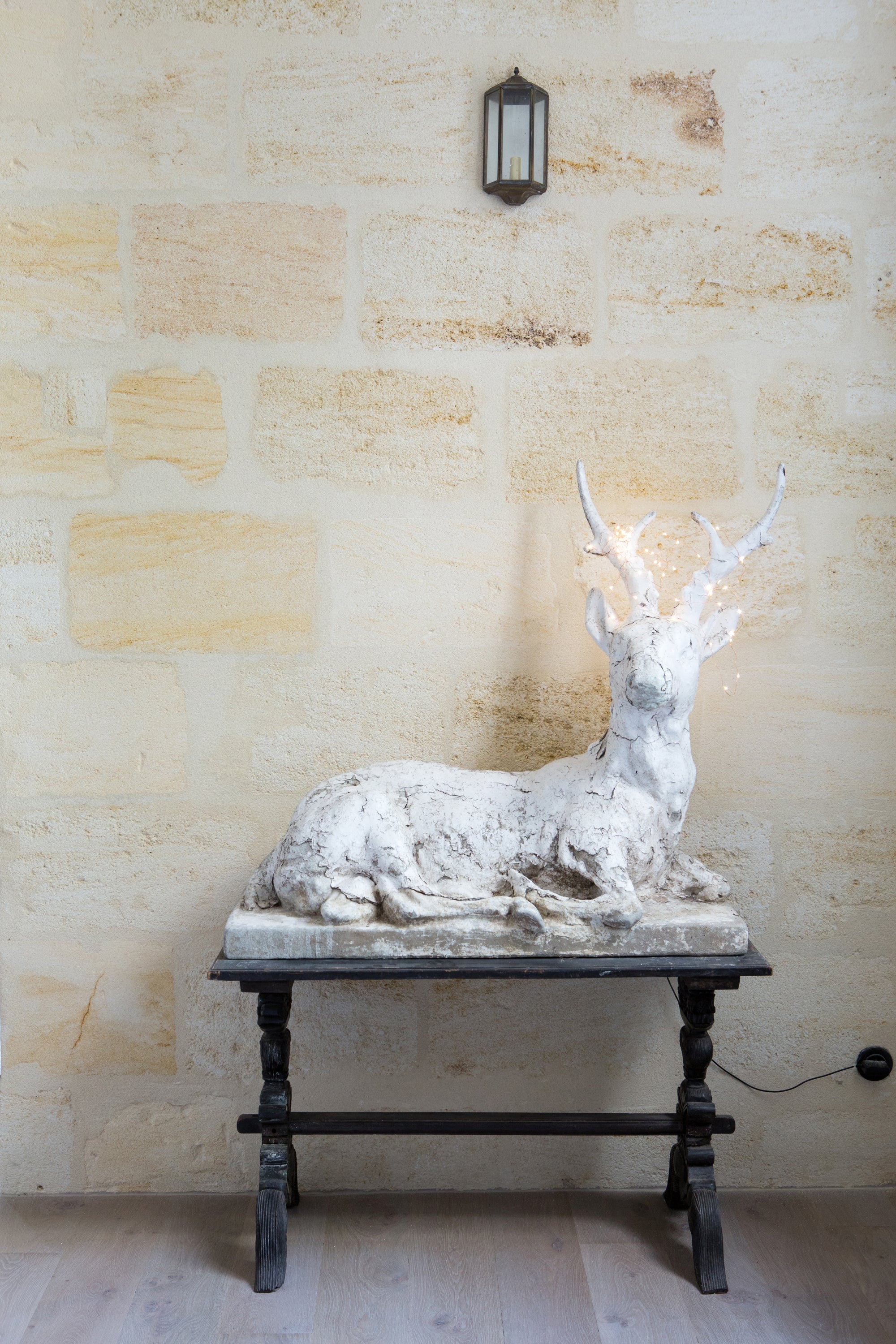 White deer sculpture on a dark wooden table against a beige wall — European property photography by Carla Coulson