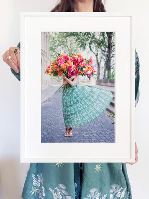 New Beginnings is a photo of a girl on the Ile St Louis in Paris with a big bunch of bright, joyous dahlias and is part of a limited edition series named Young Girl in Bloom by photographer Carla Coulson celebrating women loving and believing in themselves and building their self esteem by trusting their intuition.