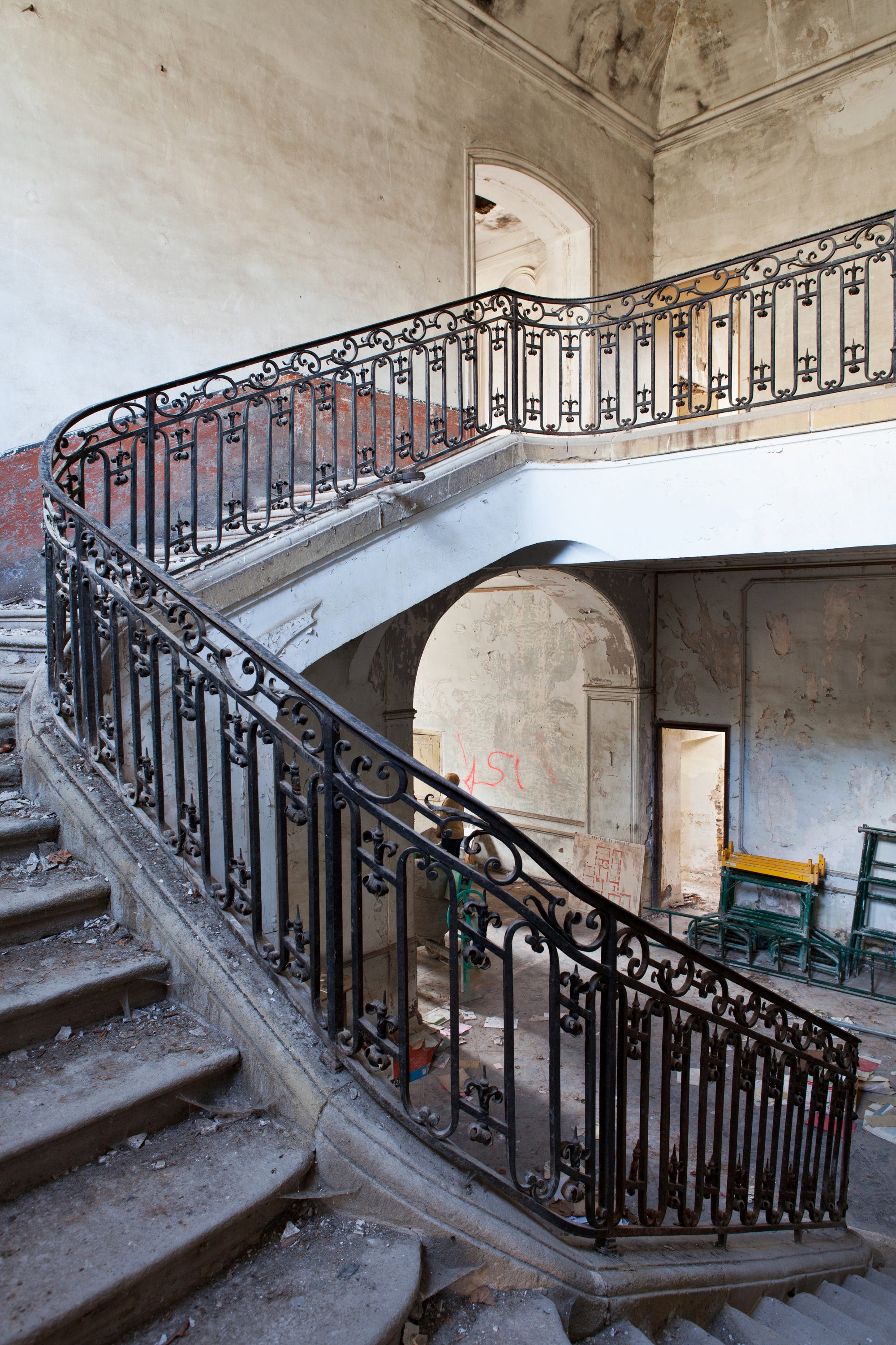 Worn staircase with ornate black railing inside an old French chateau — editorial photography by Carla Coulson