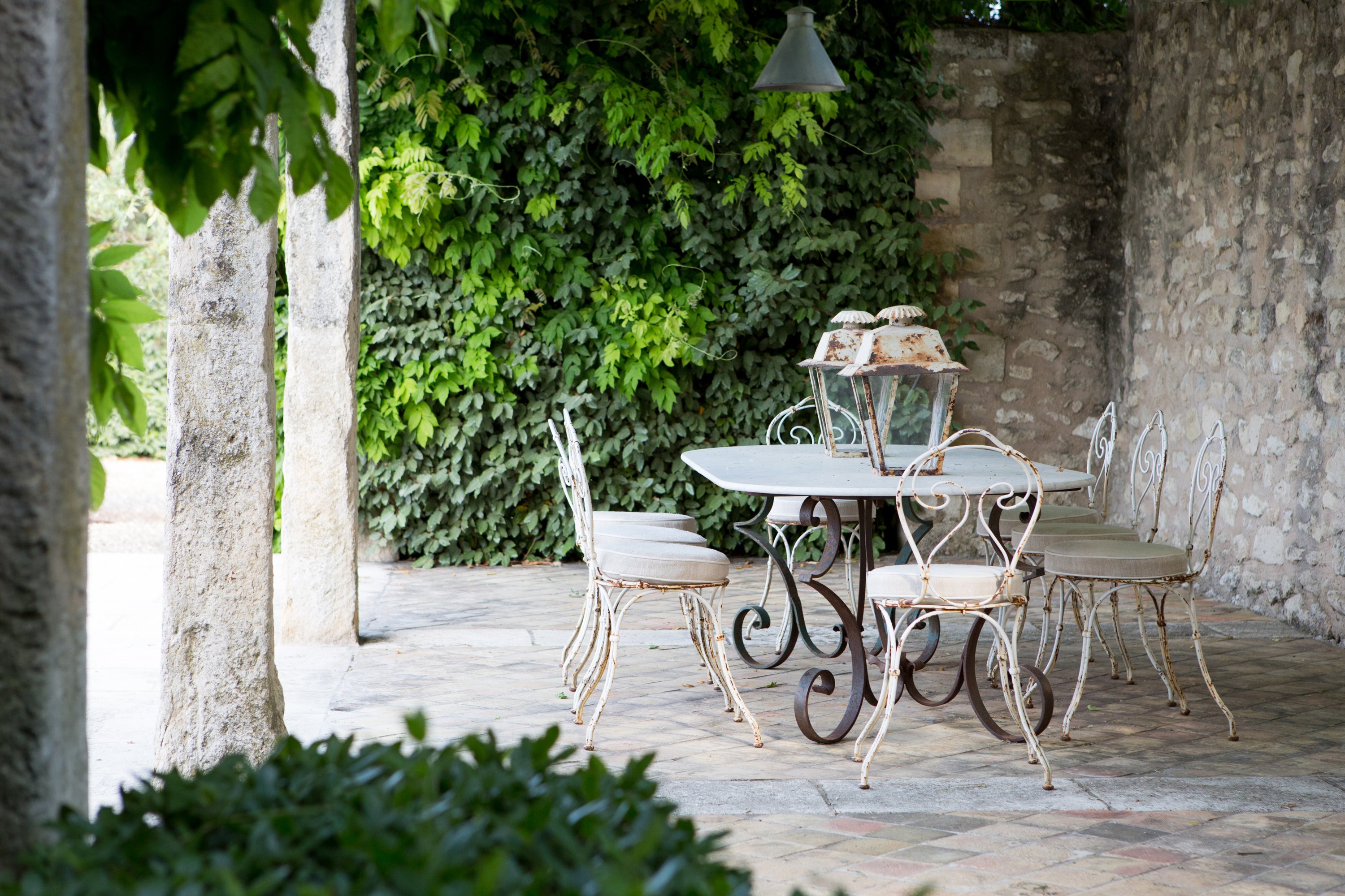 Hotel outdoor patio set with table and chairs against a stone wall and greenery — hotel lifestyle photography by Carla Coulson