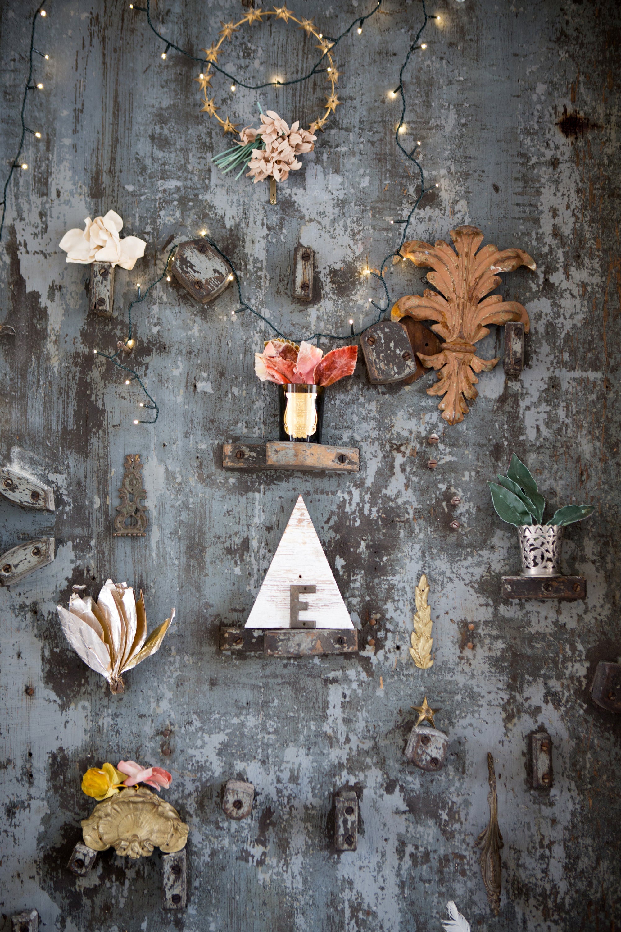 Decorative wall with various small objects and string lights on a textured surface — editorial photography by Carla Coulson