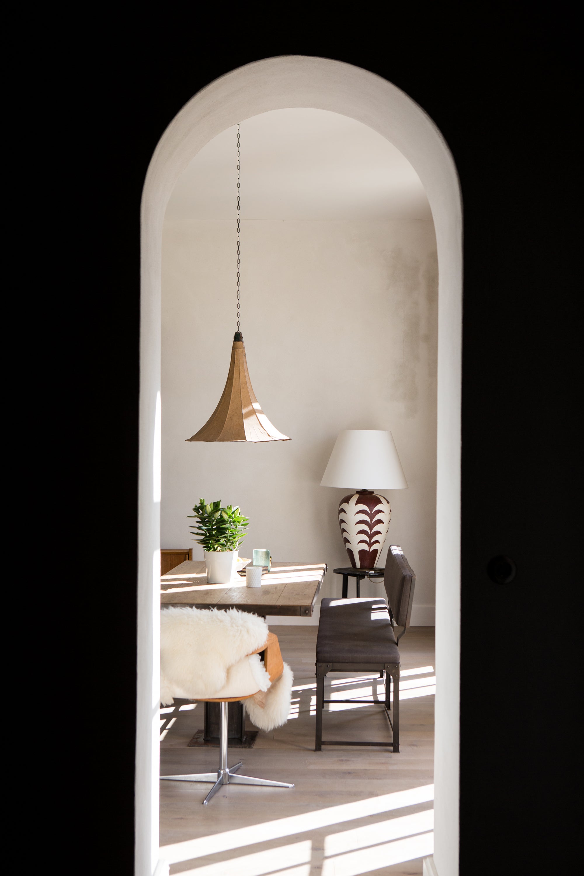 Dining room through a white archway, table, chairs, and decorative items. Luxury retreat interior with artisan styling — hotel photography by Carla Coulson
