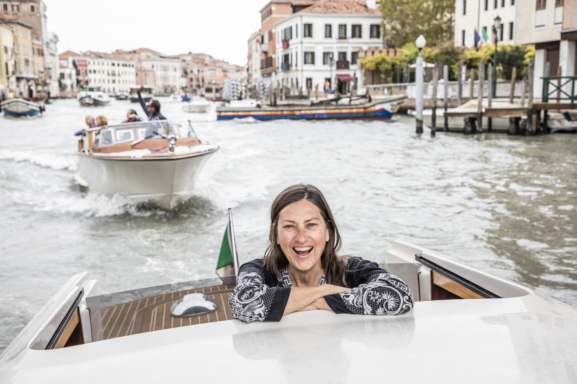 Carla Coulson rides through Venice in a water taxi smiling with joy
